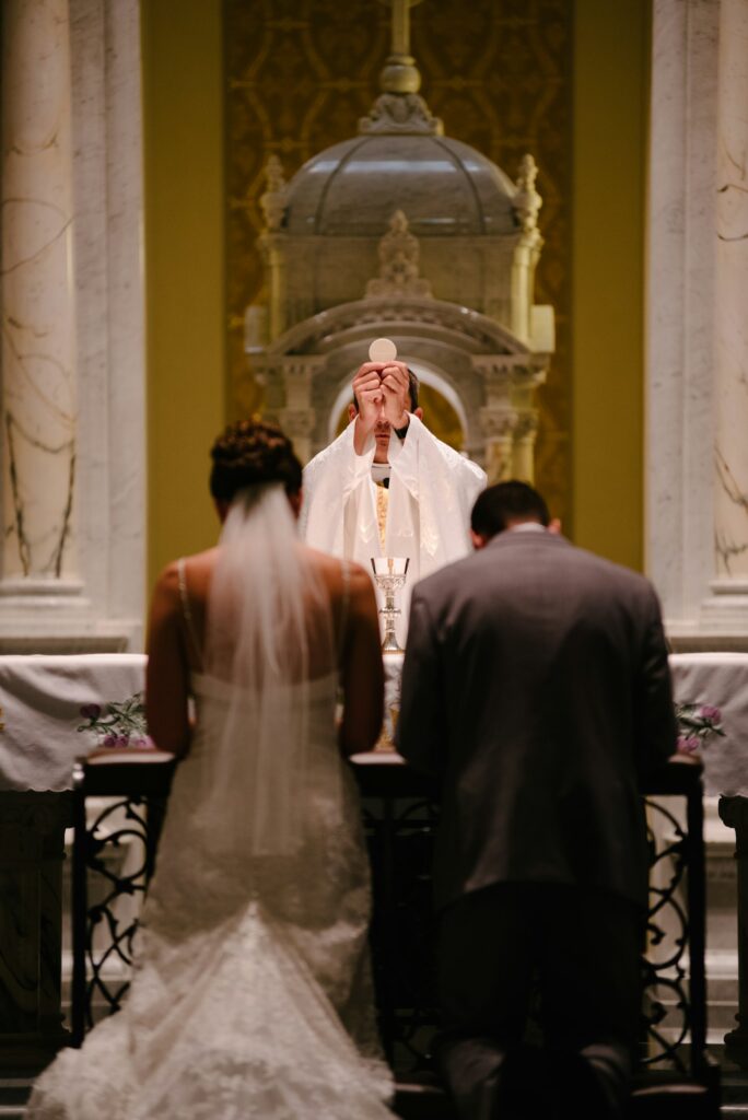 Kirchliche Trauung: Brautpaar vor dem Altar einer hellen Dorfkirche, Gäste in den Bänken