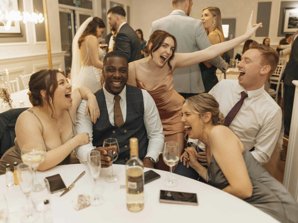 Sitzplan Hochzeit auf einer Holztafel mit Tischnamen und Blumen am Eingang einer festlich gedeckten Location