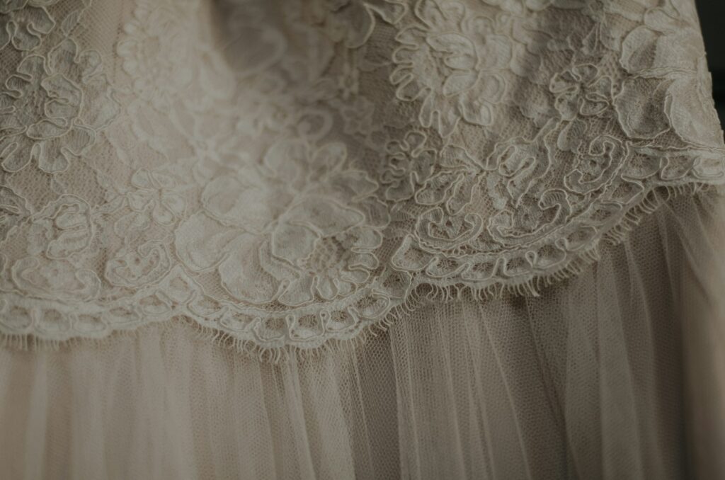 Braut im Brautkleid Boho aus Spitze mit weiten Ärmeln auf einer Sommerwiese