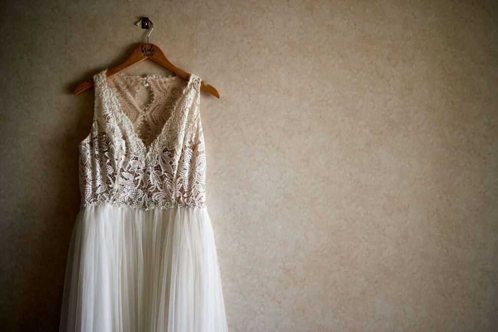 Brautkleid verkaufen: weißes Spitzenkleid hängt auf einem Bügel vor einer hellen Wand
