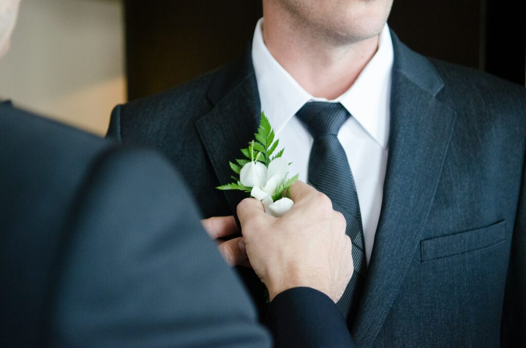 Hochzeitsanzug beim Maßnehmen: Schneider passt dem Bräutigam das Sakko an