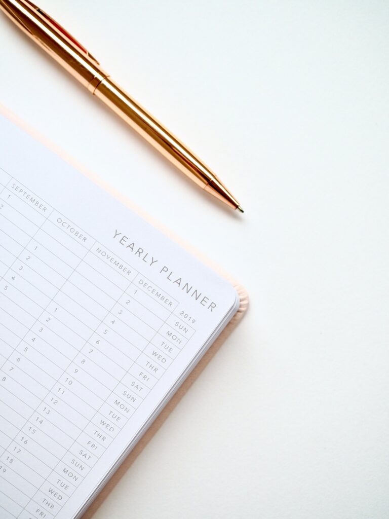 Hochzeitsplanung Checkliste auf einem Holztisch mit Kalender, Notizbuch und Eheringen