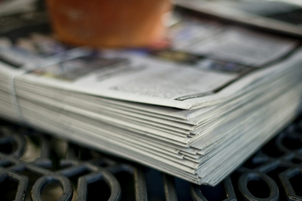 Hochzeitszeitung Ideen: aufgeschlagene, selbst gestaltete Zeitung neben Kaffeetasse und Blumen