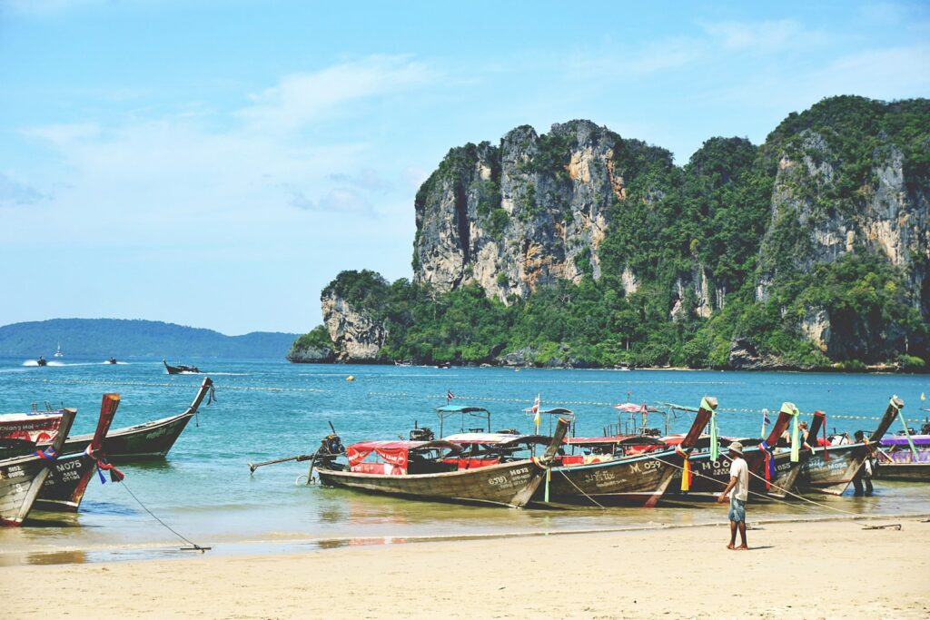 Longtailboot vor Kalksteinfelsen an einem Strand in Krabi, Flitterwochen Thailand
