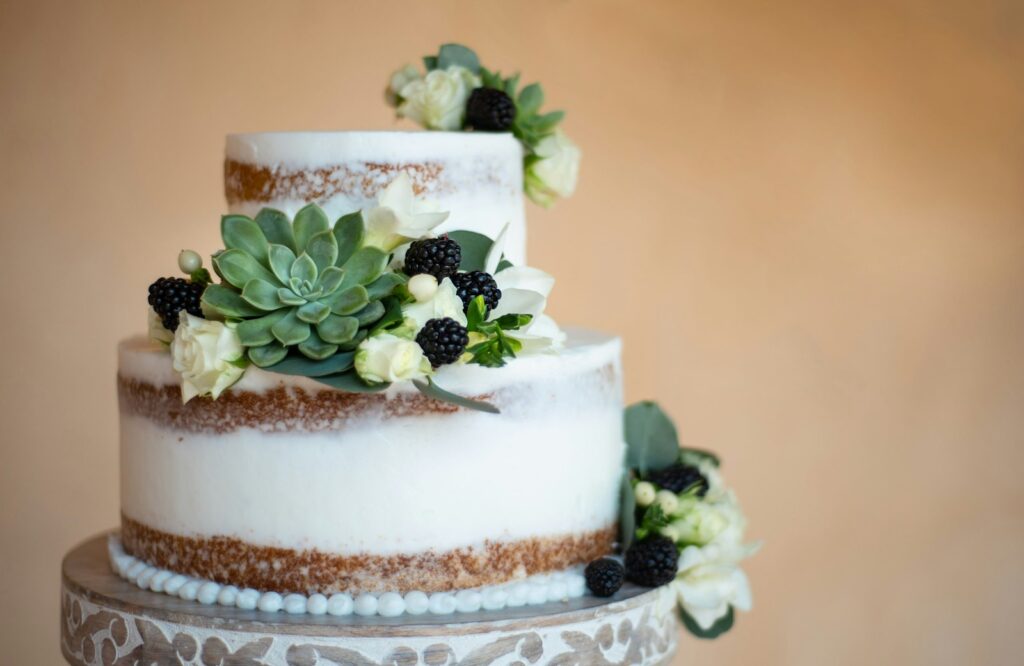 Naked Cake als Hochzeitstorte mit sichtbaren Biskuitschichten, Beeren und Blüten