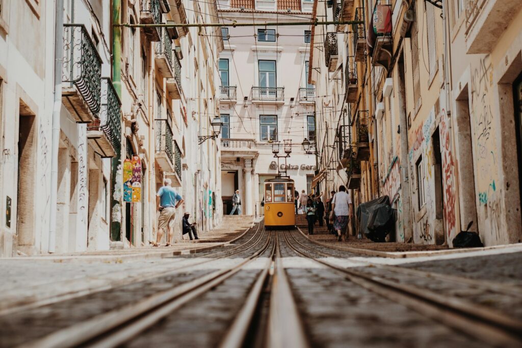 Paar in einer Altstadtgasse von Lissabon mit gelber Straßenbahn, Flitterwochen Europa in Portugal