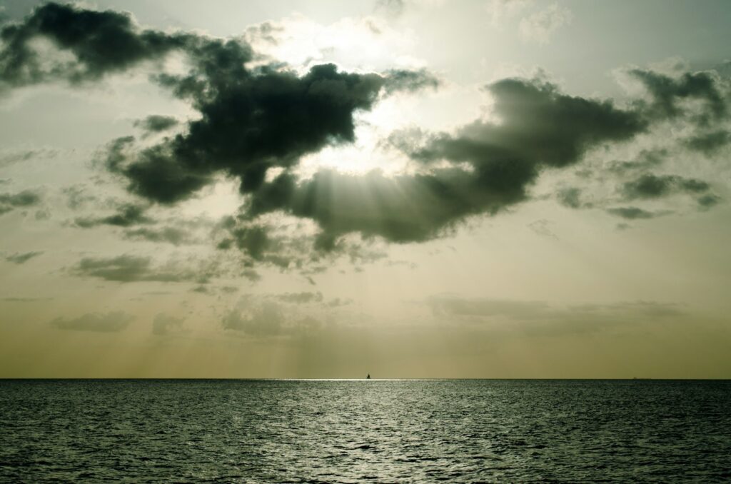 Segelboot vor einer Insel bei Sonnenuntergang, Inselhopping in den Flitterwochen Karibik